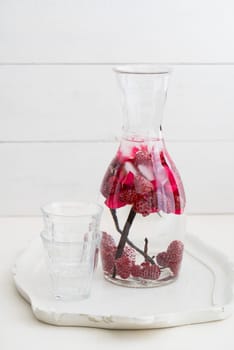 Flavoured water or infused water with raspberries,rose petals and vanilla in a carafe