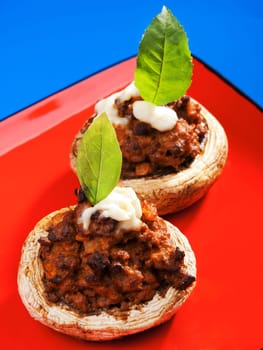Stuffed mushrooms with meat and mozzarella decorated with fresh basil, izolated on green background