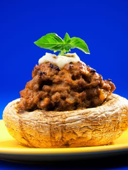 Stuffed mushrooms with meat and mozzarella decorated with fresh basil, izolated on green background