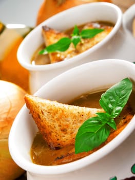 Famous onion soup with onions and olive oil in the background, close up