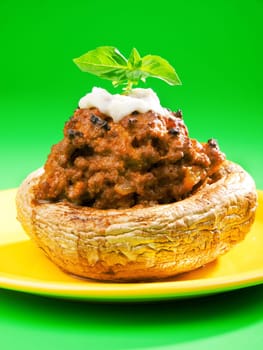 Stuffed mushrooms with meat and mozzarella decorated with fresh basil, izolated on green background