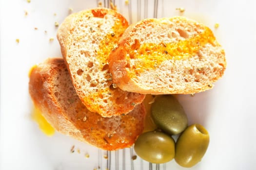 Homemade baguettes with ovile oil and green olives, served as appetizer