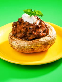 Stuffed mushrooms with meat and mozzarella decorated with fresh basil, izolated on green background