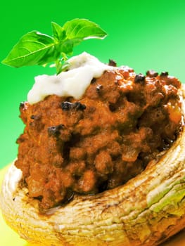 Stuffed mushrooms with meat and mozzarella decorated with fresh basil, izolated on green background