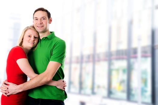young couple in embrace in front of bright background