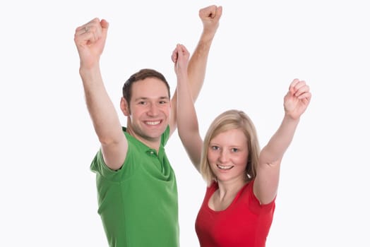 young happy couple in front of white background with arms up