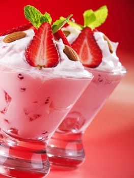 Strawberry cream in two glasses garnished with strawberries, almonds and fresh mint