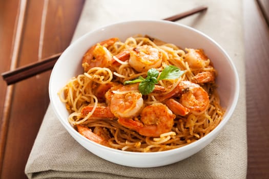 Thai rice noodles with shrimps in a bowl with chopsticks