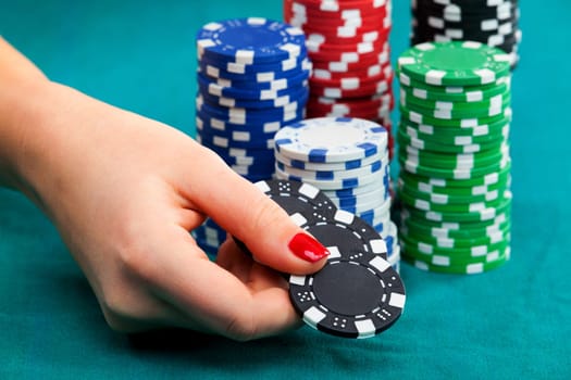 Young woman holding gambling chips on black background