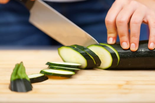 Young woman cutting zucchini in the kitchen