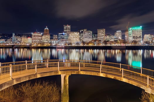 Portland Oregon downtown city skyline from pedestrian bridge along Willamette River at night