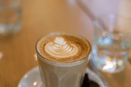 Caffe Latte with Leaf Shape Milk Foam Pattern in Glass Cup Closeup