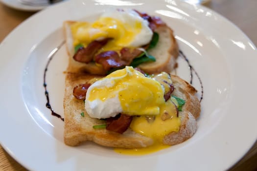 Eggs Benedict with Bacon Strips Spinach and Hollandaise Sauce Closeup