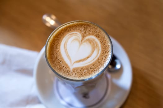 Caffe Latte with Heart Shape Milk Foam Pattern in Glass Cup Closeup