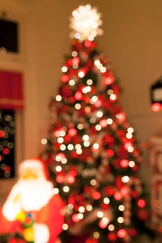 Christmas Tree Decorated with Lights Candy Cane Ornaments Tree Topper and Santa Claus Statue Blurred Defocused Bokeh Background