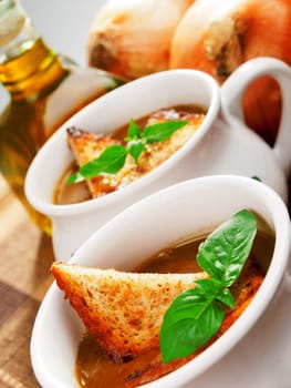 Famous onion soup with onions and olive oil in the background, close up