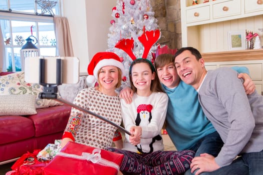 Two Generation Family taking a Selfie at Christmas. They are wearing novelty items and Smiling at the Camera.
