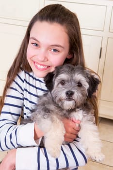 Young girl holding a Puppy. She is looking at the Camera and smiling.