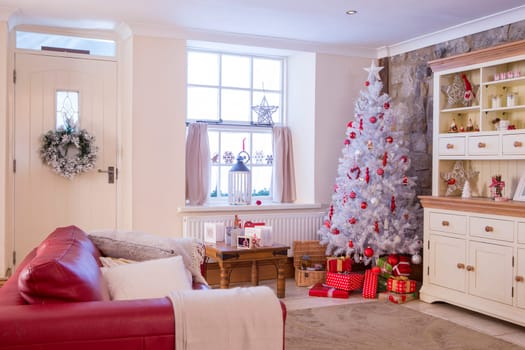 A Horizontal Image of a Living Room dressed for Christmas. Colours mainly Red and White and spacious. No People.