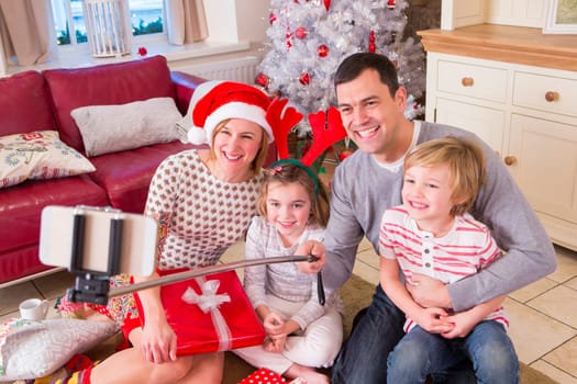 Two Generation Family taking a Selfie at Christmas. They are using a Selfie Stick and Smiling at the Camera.