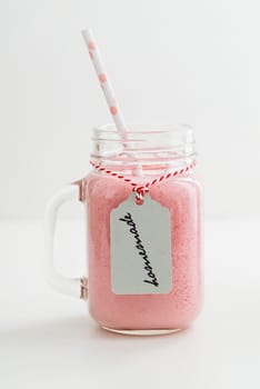 Pink healthy smoothie with yoghurt and berries in glass with pendant with handwritten homemade lettering