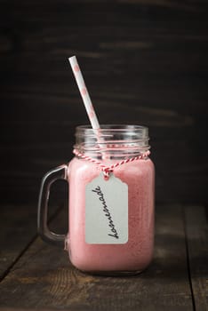Pink healthy smoothie with yoghurt and berries in glass with pendant with handwritten homemade lettering
