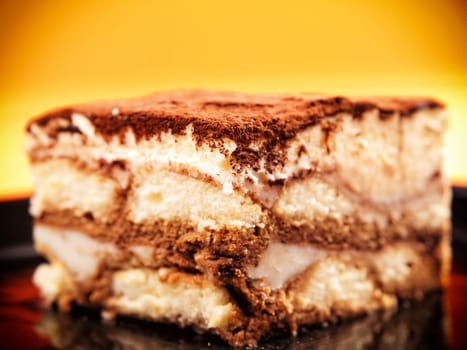 Tiramisu cake in a black plate, close up
