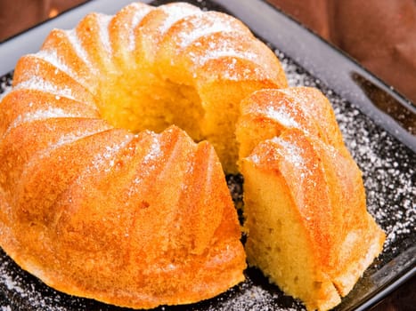 Vanilla cake with one piece of it on brown background