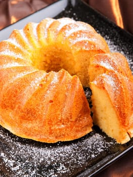 Vanilla cake with one piece of it on brown background