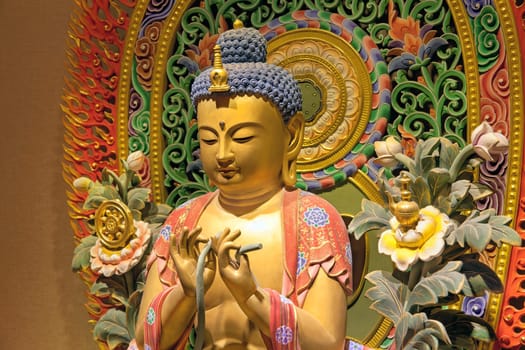 Wood Carved Colorful Sitting Buddha Statue with Intricate Colorful Background Closeup