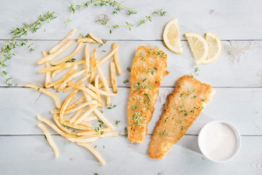 Fish and chips. Top view fried fish fillet with french fries on wooden background.