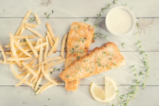 Fish and chips. Above view fried fish fillet with french fries on wooden background, vintage tone.