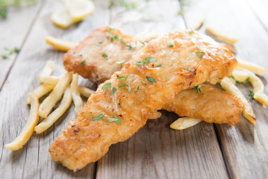 Fish and chips. Fried fish fillet with french fries on old wooden background. Fresh cooked with hot steams.
