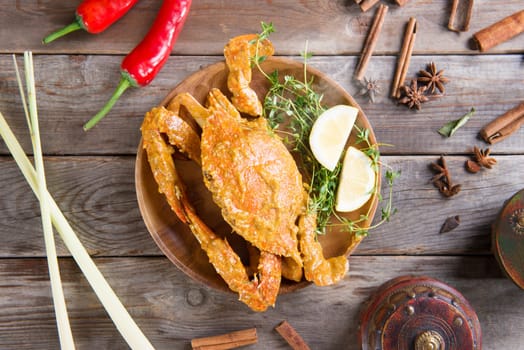 Above view cooked delicious hot and spicy sauce blue crab and ingredients, on wooden background. Fresh cook with hot smoke steams.