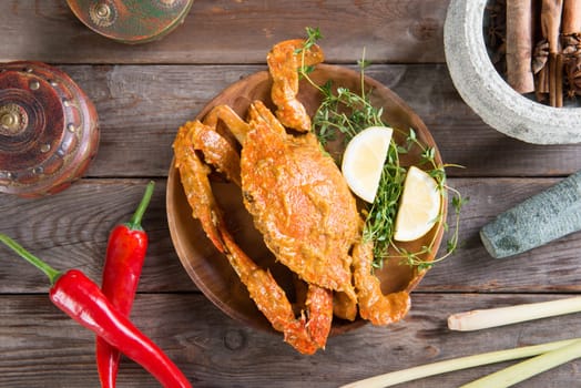 Top view cooked delicious hot and spicy sauce blue crab and ingredients, on wooden background. Fresh cook with hot smoke steams.