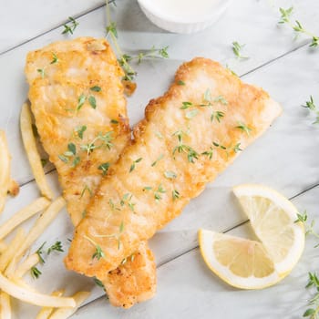 Fish and chips. Above view fried fish fillet with french fries on wooden background.