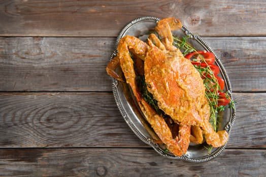 Top view cooked delicious hot and spicy sauce blue crab, on wooden background with copy space. Fresh cook with hot smoke steams.