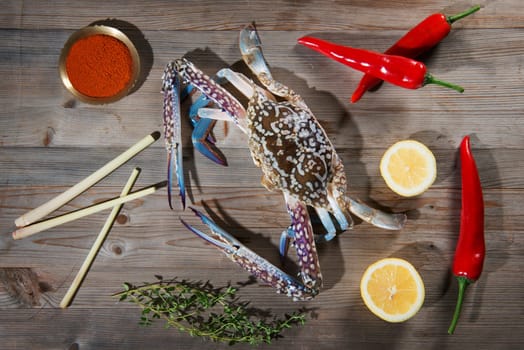 Above view raw blue crab and ingredients ready to cook, on wood background.