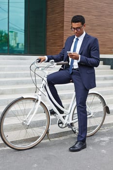 Elegant businessman using cellphone while sitting on bicycle