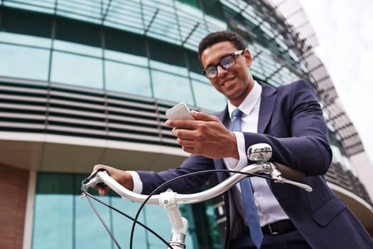 Young businessman on bicycle reading sms in urban environment