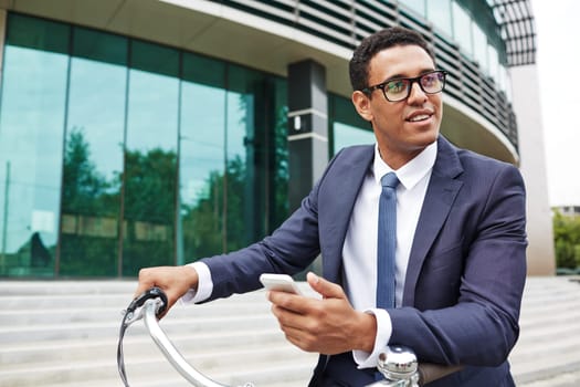 Young businessman with cellphone standing by modern building