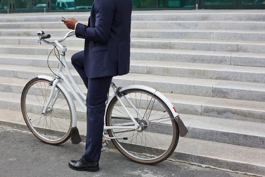 Man in suit writing or reading sms while sitting on bicycle