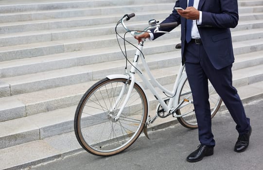 Businessman with cellphone walking along stairs with bicycle