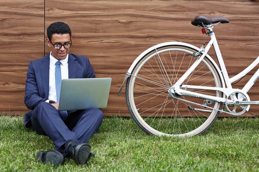 Young businessman with laptop networking against wooden wall