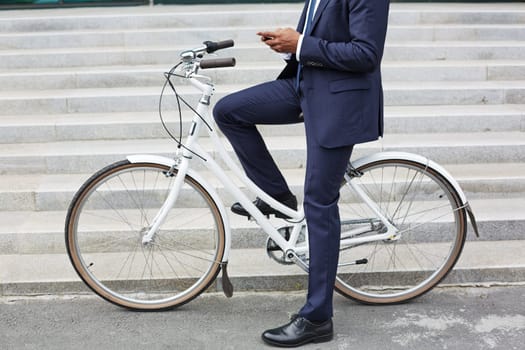 Modern businessman on bicycle writing sms in urban environment