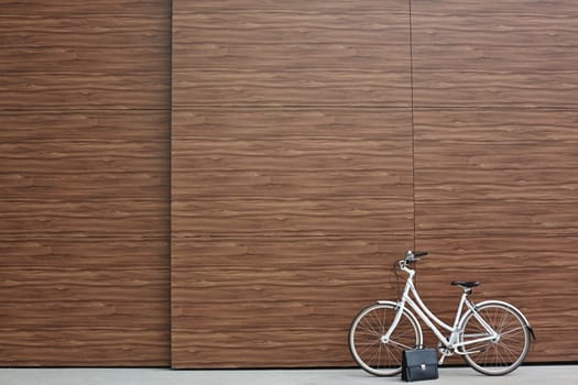 Bicycle and black briefcase against wooden wall