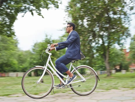 Modern businessman riding bicycle in park