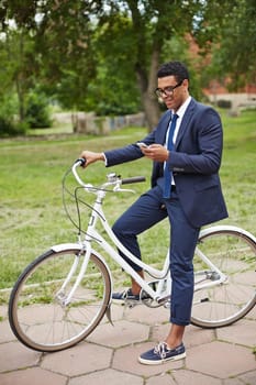 Modern and active employee with cellphone and bicycle reading sms in park