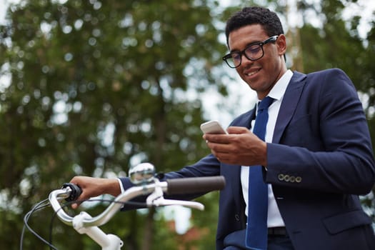 Happy modern businessman using cellphone in park