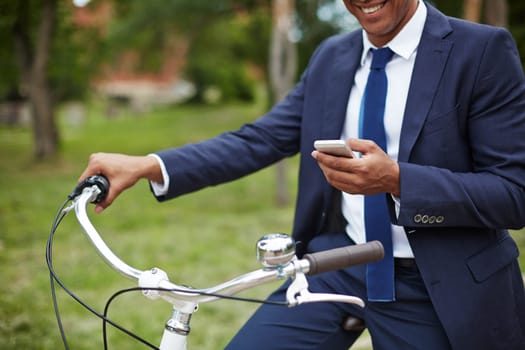 Close-up of young businessman with cellphone sitting on bicycle in park